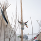 A cow skull tied to a pole in front of a tipi at camp.